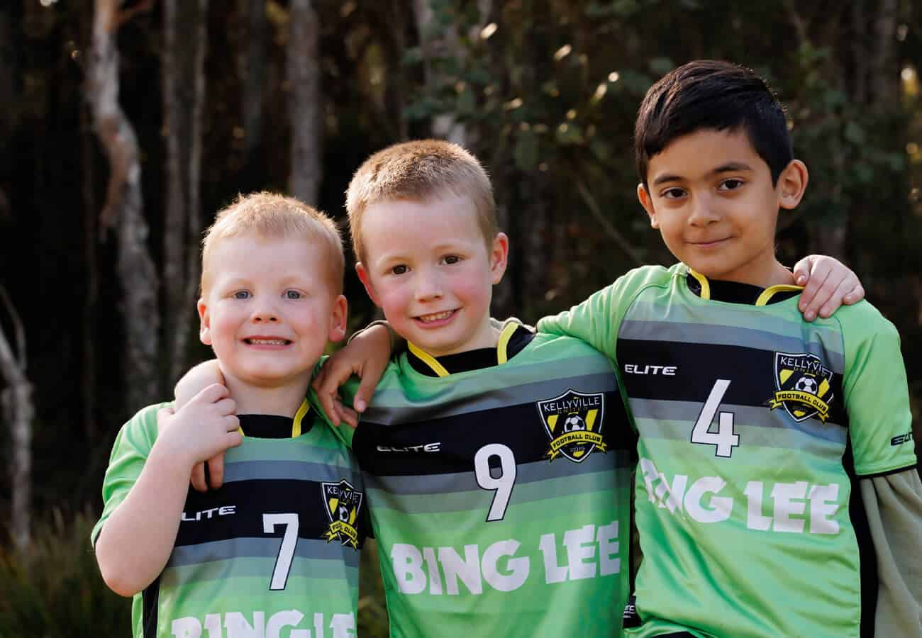 3 young football players in the minis program with arms around each other